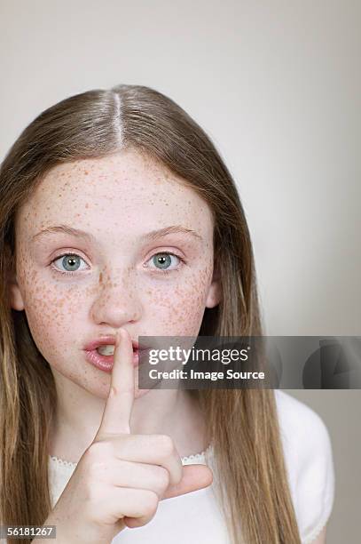 girl putting a finger to her lips - kid putting finger in mouth stock-fotos und bilder