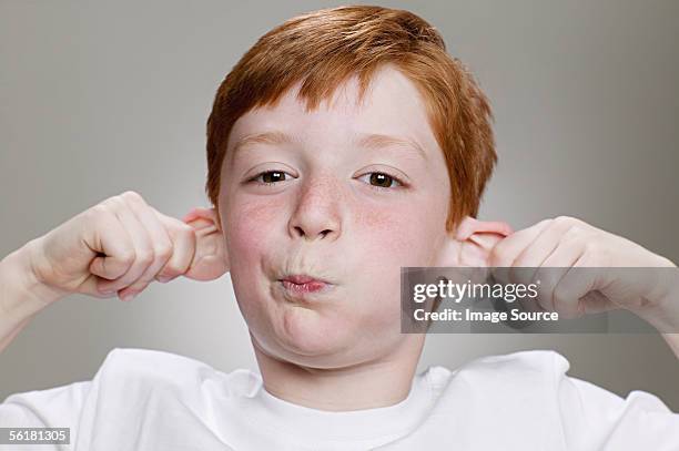 boy pulling a funny face - pulling ear stock pictures, royalty-free photos & images