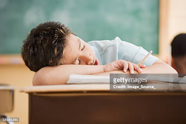 ragazzo dorme sulla scrivania - tired foto e immagini stock