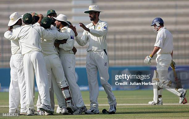 The Pakistan team celebrates as Andrew Strauss walks of after being dimissed on day five of the First Test Match between England and Pakistan on...