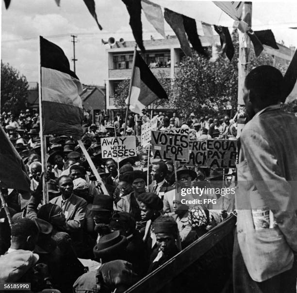 South Africans march in the street and hold banners to protest the new restrictions on African citizens, soon to be known worldwide as Apartheid,...