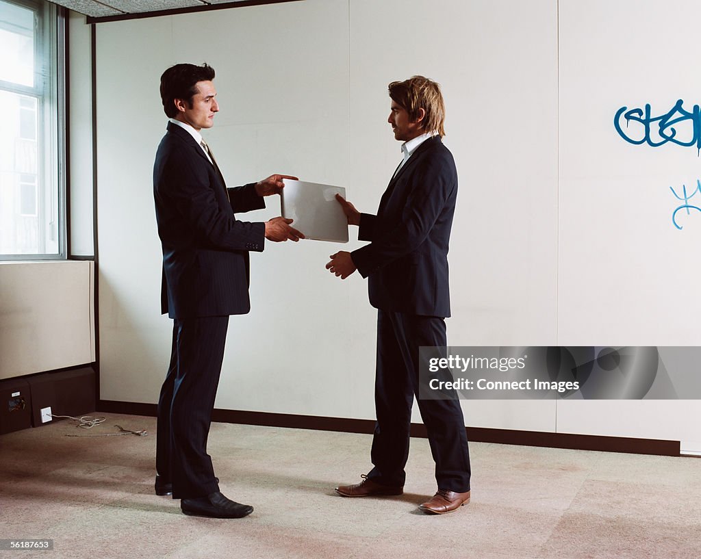 Businessmen exchanging a laptop computer