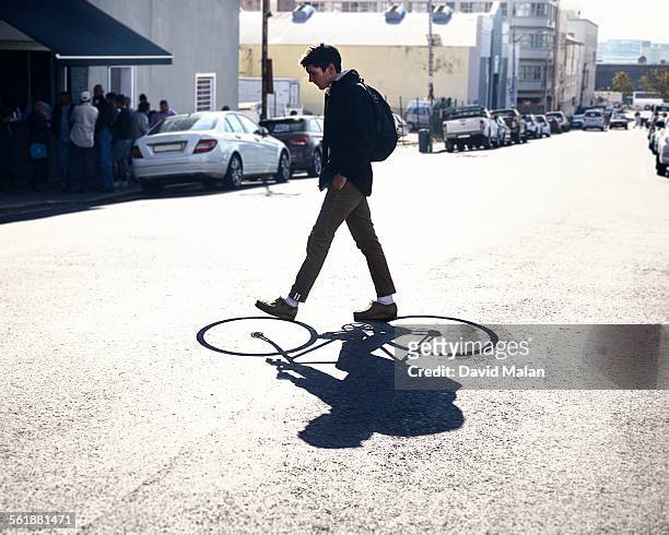 young adult walking with a cycling shadow - blickwinkel der aufnahme stock-fotos und bilder