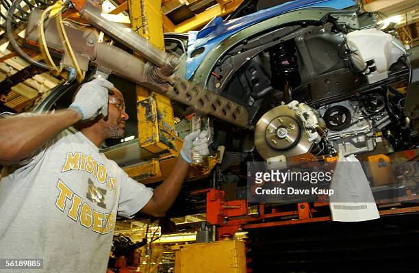 Ford Motor Company auto worker Robert Robertson installs the engine into a Mercury Mariner Hybrid at the Kansas City Assembly Plant on November 16,...