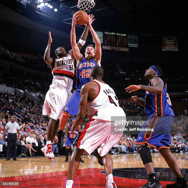 David Lee of the New York Knicks takes the ball to the basket between Zach Randolph and Theo Ratliff of the Portland Trail Blazers during a game at...