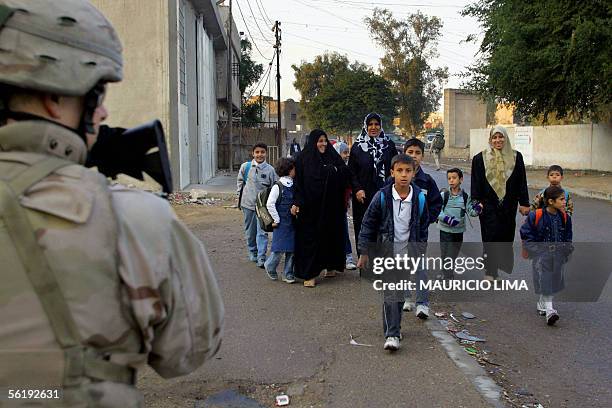 Group of Iraqi mothers take their children to the school as a US soldier from 4-64 Battalion, 3rd Infantry Division walks past by them during an...