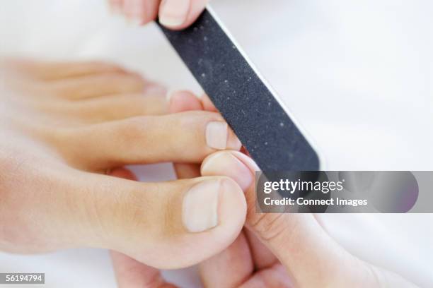 woman receiving podiatry treatment - nagelfeile stock-fotos und bilder