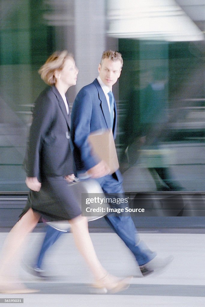 Businessman and businesswoman walking briskly