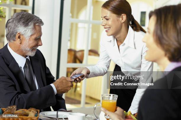 waitress handing cell phone to businessman - md spa get stock pictures, royalty-free photos & images