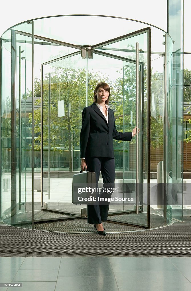 Businesswoman walking through revolving door