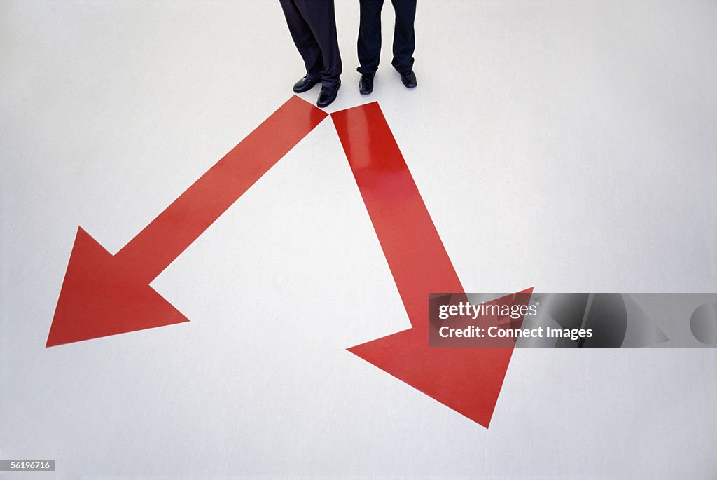 Men standing between direction arrows