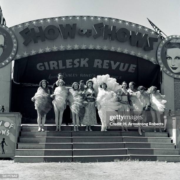 1930s: Group Of Fan Dancers Standing At Top Of Stairs, In Front Of Entrance To Traveling Show, With A Curtain Reading "Girlesk Revue".