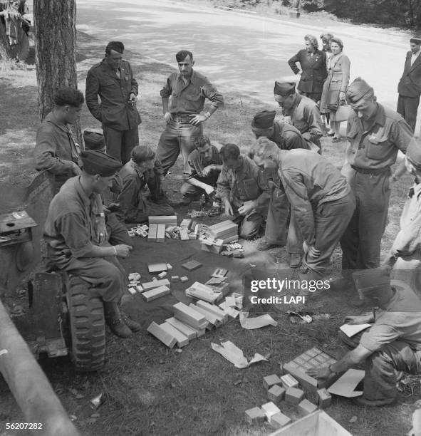 War 1939-1945. Liberation of Paris. Soldiers of the 2nd A.D. With the wood of Boulogne. Sharing tobacco, chewing-gum, chocolate, tooth powder etc......