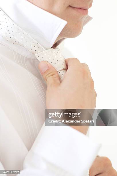 smiling groom tying tie, close-up - santorini wedding stockfoto's en -beelden