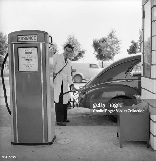 Petrol pump attendant filling up a 203 Peugeot in a BP service station. Deauville , about 1952.