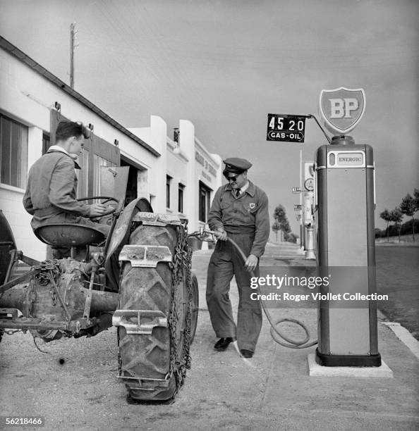 Petrol pump attendant filling up the diesel oil of a tractor in a BP service station. France, about 1952.