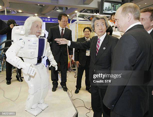 Japanese Prime Minister Junichiro Koizumi and Russian President Vladimir Putin look at a humanoid robot during a visit to the IT exhibition during...