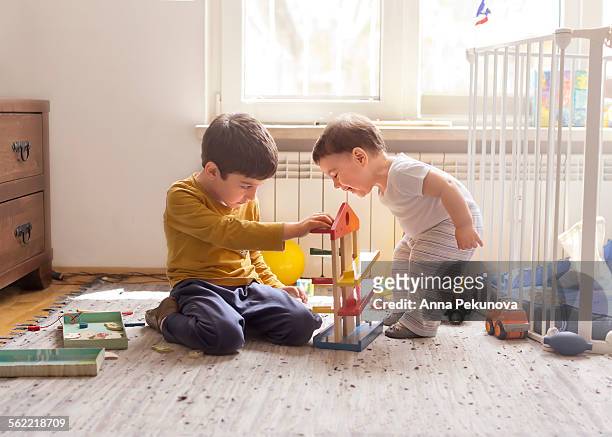sibling playing together with wooden toy - children playing with toys stockfoto's en -beelden
