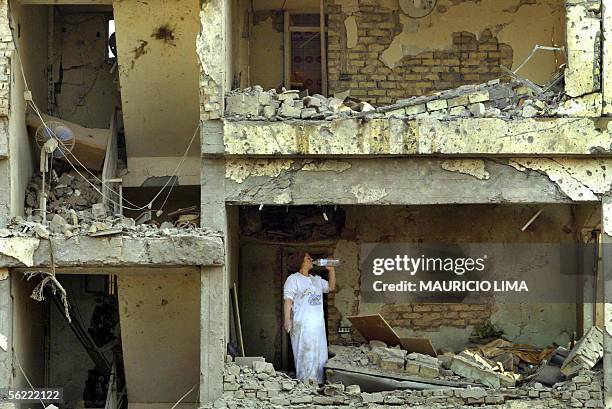 An Iraqi woman drinks water as she tries to rescue personal belongings inside her collapsed apartment at the site where two suicide bombers detonated...