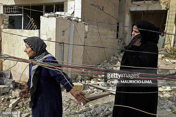 Iraqi women look at their destroyed residence at the site where two suicide bombers detonated explosives-laden cars near Al Hamra hotel that houses...