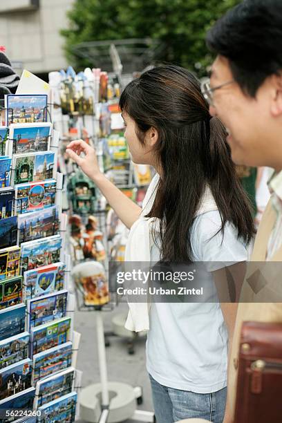 young asian woman next to a man picking a postcard from a rack, selective focus - rack focus stock-fotos und bilder