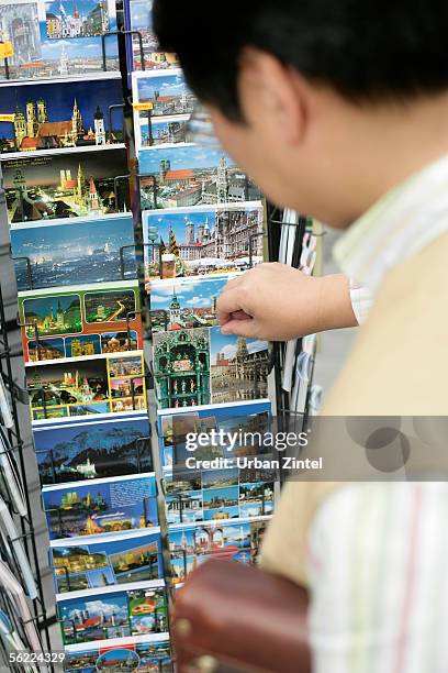asian man looking for a postcard in a rack, selective focus - rack focus stock-fotos und bilder