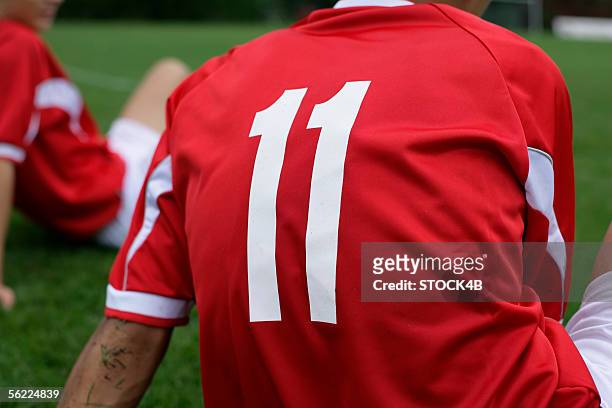 soccer player wears number 11 sitting on grass - eleventh stock-fotos und bilder