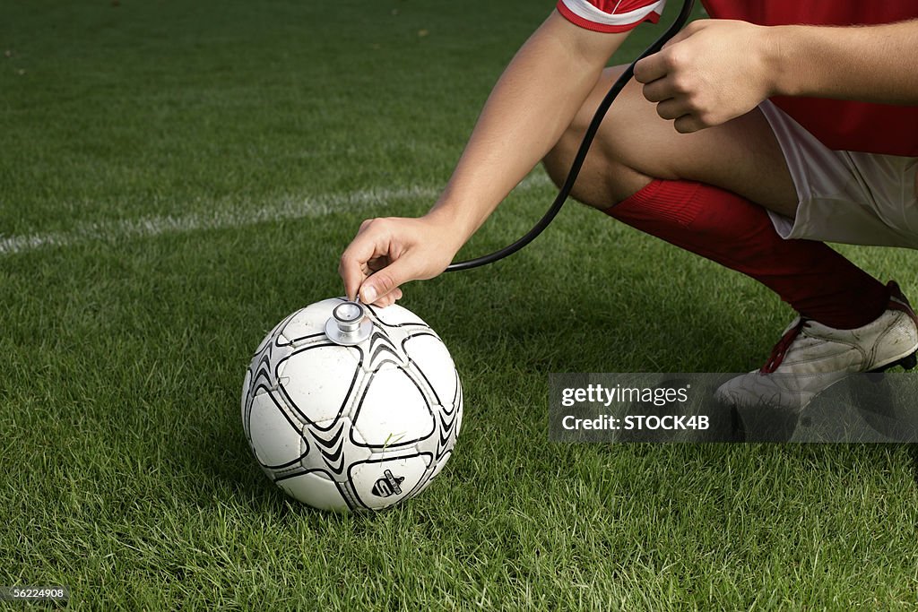 Soccer player checking football with a stethoscope