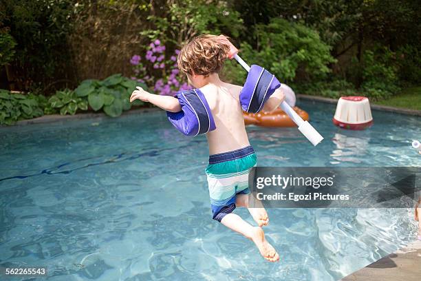 boy jumping into swimming pool - arschbombe stock-fotos und bilder