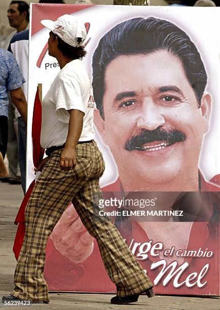 Una mujer camina frente a un cartel de propaganda del candidato presidencial Manuel Zelaya Rosales, del Partido Liberal el 19 de noviembre de 2005 en...
