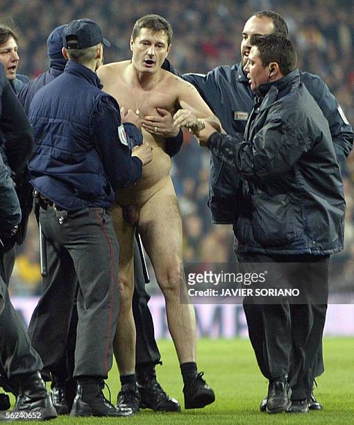 Security men hold a streaker during their Spanish League football match between Real Madrid and Barcelona at Santiago Bernabeu stadium in Madrid, 19...