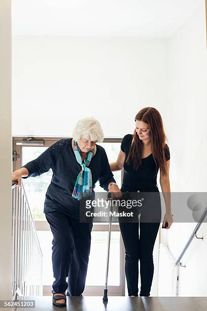young woman helping grandmother to climb steps - grandma cane stock pictures, royalty-free photos & images