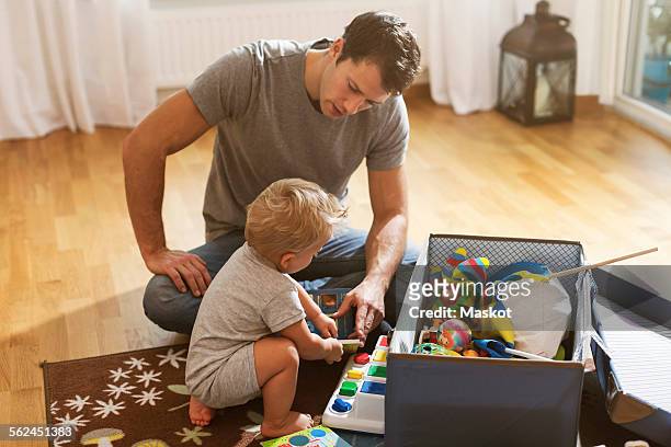 father and baby boy playing toys on floor at home - toy box stock pictures, royalty-free photos & images