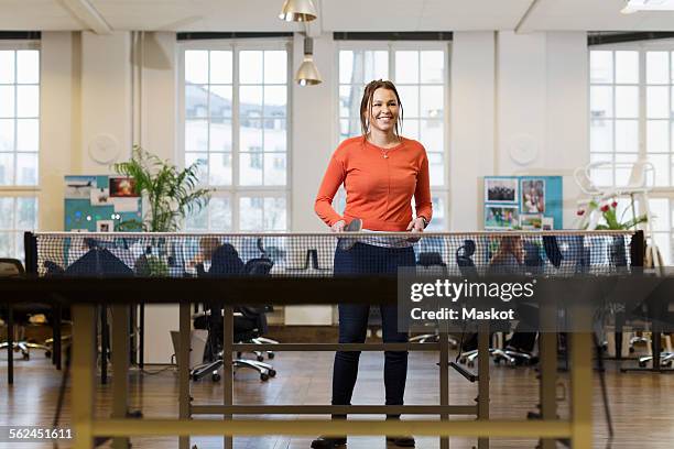 happy businesswoman playing table tennis in creative office - office ping pong stock pictures, royalty-free photos & images