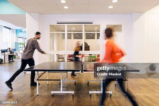 blurred motion of business people playing table tennis in creative office - table tennis player stock pictures, royalty-free photos & images