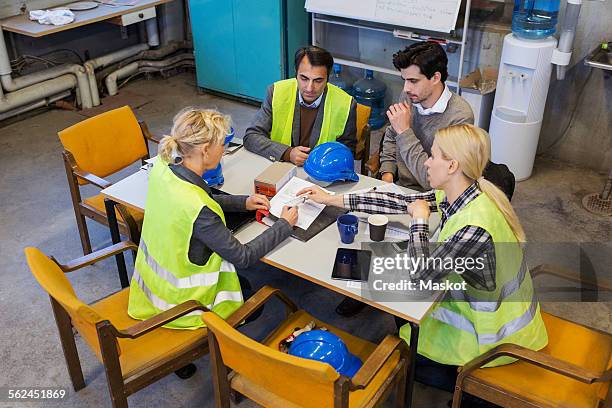 manual workers planning at table in factory - four people and meeting stock pictures, royalty-free photos & images
