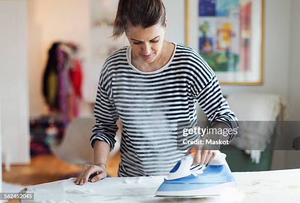 woman ironing cloth in house - ferro da stiro foto e immagini stock