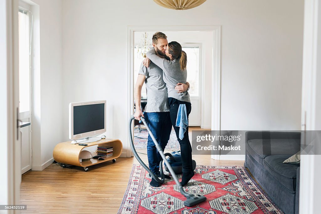 Full length of couple kissing while cleaning home