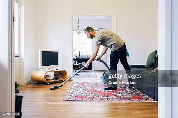 side view of man vacuuming hardwood floor - aspirador fotografías e imágenes de stock