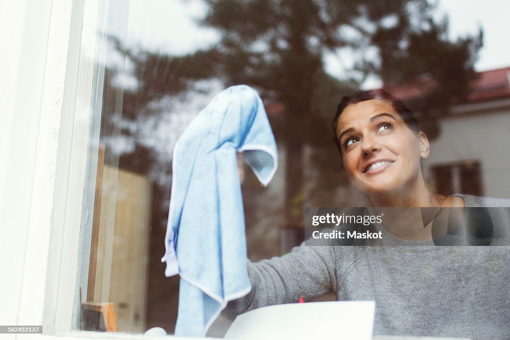 Woman cleaning glass of house window