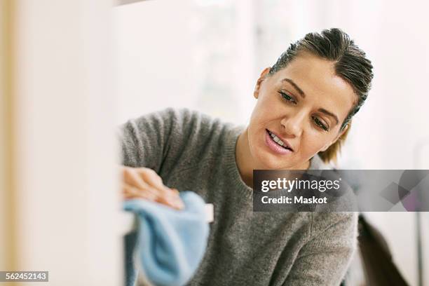 woman cleaning shelf with rag - spolverare foto e immagini stock