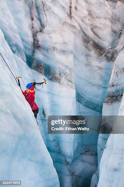 an ice climber swings his ice tools in a moulin on the root glacier in wrangell-st. elias national park, alaska. - root glacier stock-fotos und bilder