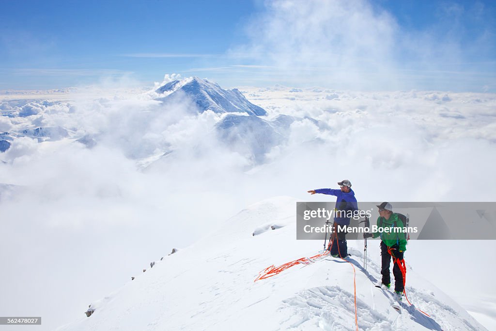 Two High Mountain Rangers are taking a rest on the West Rib on Mount McKinley, Alaska. Mount Hunter in the background.