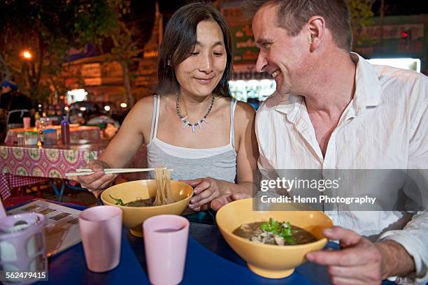 couple eating noodle soup at thai open air market - thai food stock pictures, royalty-free photos & images