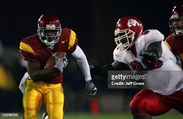 Reggie Bush of the USC Trojans carries the ball past Louis Leonard of the Fresno State Bulldogs during the game at the Los Angeles Memorial Coliseum...
