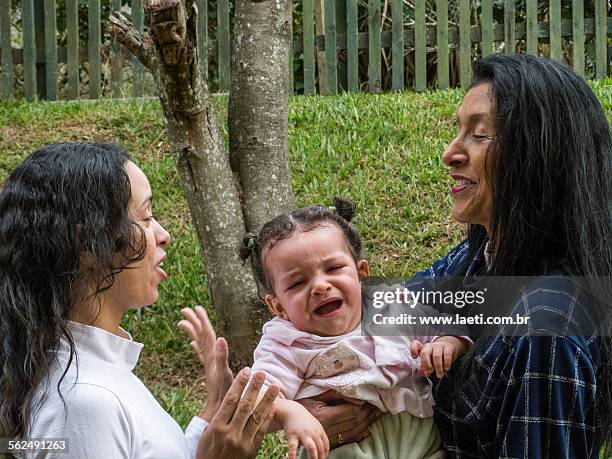 women talking with a child crying. - mulheres photos et images de collection