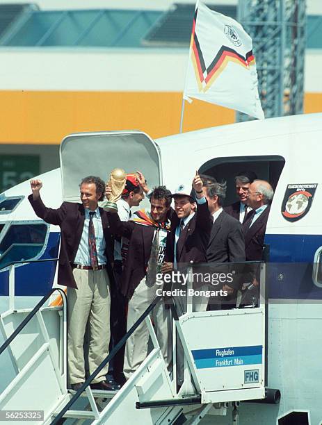 Germany's head coach Franz Beckenbauer celebrates with Pierre Littbarski and Lothar Matthaeus during the arrival of the German Football National Team...