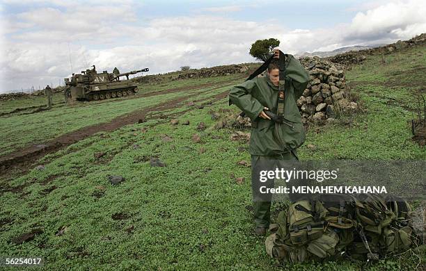 Israel: An Israeli artillery unit soldier slings his rifle across his shoulder as he stands close to a 155mm canon mounted on an armoured vehicle...