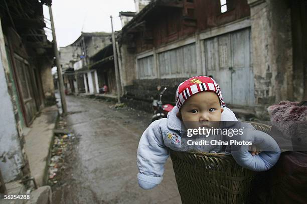 Baby sits in a basket in the Dachang Township on November 16, 2005 in Wushan County of Chongqing Municipality, southwest China. The Township's site...