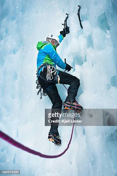 male mountain climber scales ice covered rock wall - crampon stock-fotos und bilder